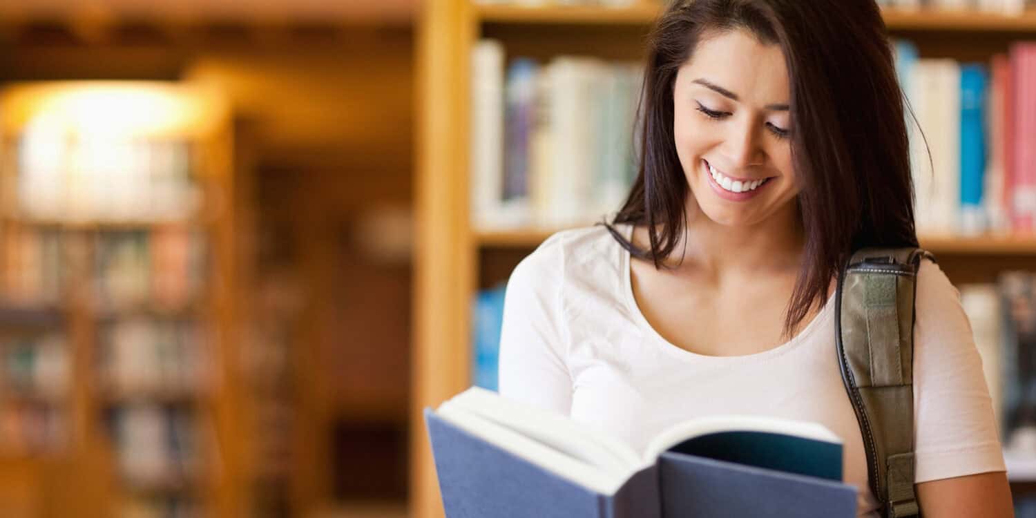 Cute student reading a book improving vocabulary